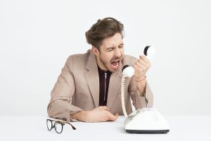 An angry man an screams into a telephone.