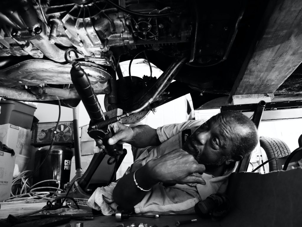 Mechanic working on the underside of a vehicle.
