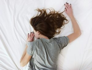 woman laying on mattress, face down.