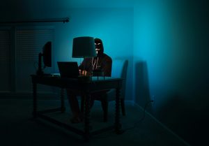 hacker sitting at desk in low light.