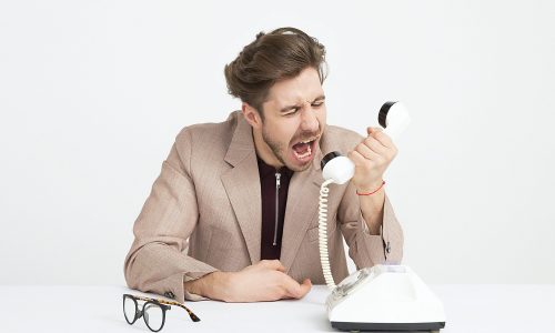 An angry man an screams into a telephone.