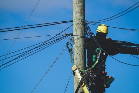 A telephone worker works on top a telephone pole with cable lines.