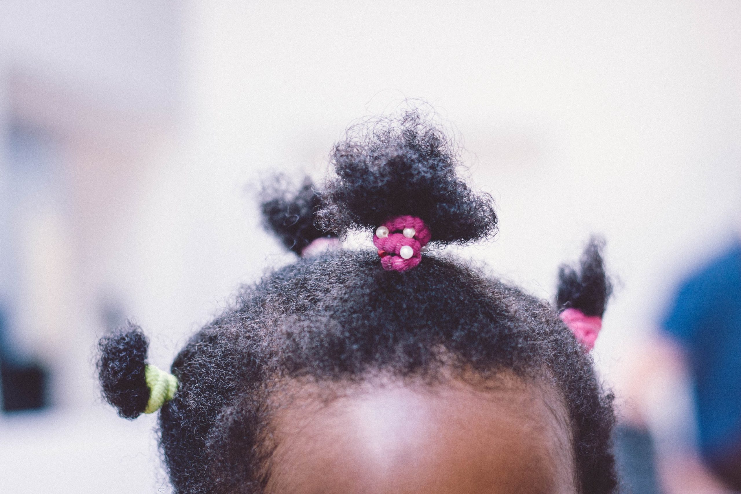 A young black girl has her hair knotted before being styled.