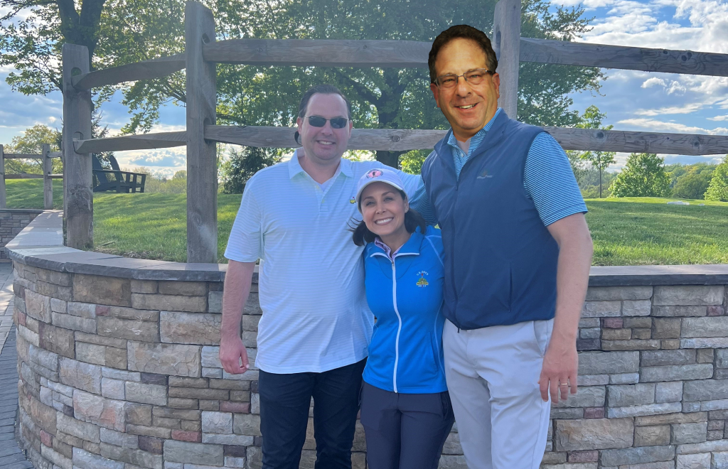 Shub & Johns attorneys, Benjamin Johns, and Sam Holbrook, pictured with a man, whose head is altered to represent Shub & Johns partner Jonathan Shub, on a Golf field.